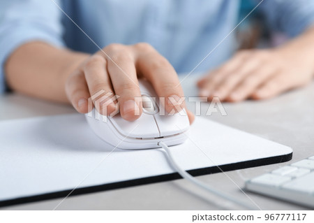 Woman using wired computer mouse on pad at light grey marble table, closeup Woman using wired computer mouse on pad at light grey marble table, closeup 96777117