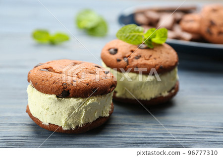 Sweet delicious ice cream cookie sandwiches on blue wooden table, closeup 96777310