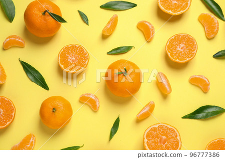 Flat lay composition with fresh ripe tangerines and leaves on light yellow background. Citrus fruit 96777386