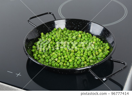 Cooking frozen sweet peas on induction stove. Vegetable preservation 96777414