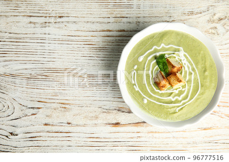 Delicious broccoli cream soup with croutons served on white wooden table, top view. Space for text 96777516
