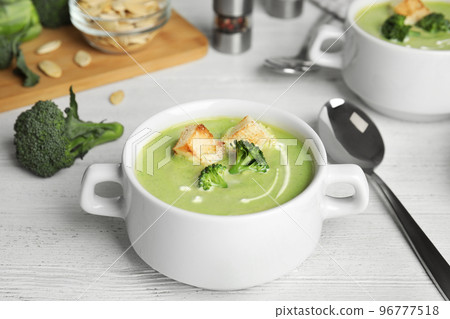 Delicious broccoli cream soup with croutons served on white wooden table 96777518