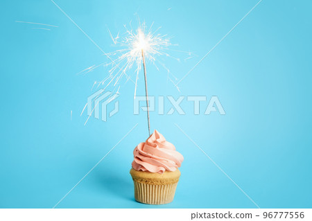 Birthday cupcake with sparkler on light blue background 96777556