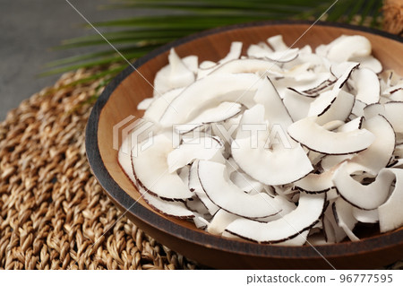 Tasty coconut chips on wicker mat, closeup Tasty coconut chips on wicker mat, closeup 96777595
