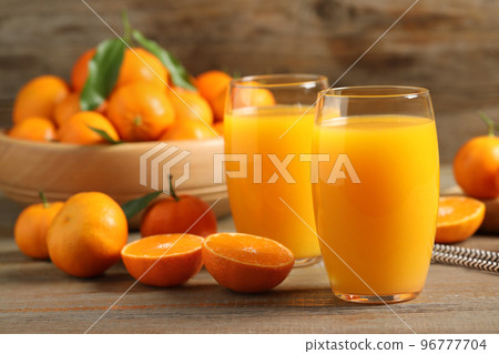Glasses of fresh tangerine juice and fruits on wooden table Glasses of fresh tangerine juice and fruits on wooden table 96777704
