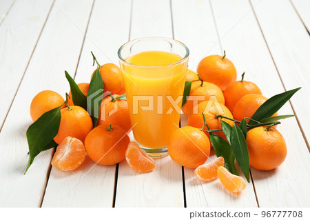 Glass of fresh tangerine juice and fruits on white wooden table 96777708