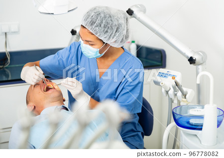 Female dentist examines the oral cavity of female patient. Dental treatment in dental clinic Female dentist examines the oral cavity of female patient. Dental treatment in dental clinic 96778082
