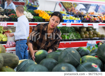 Woman choosing watermelon in fruit and vegetable department of supermarket Woman choosing watermelon in fruit and vegetable department of supermarket 96778241