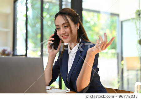 Elegant Asian businesswoman talking on the phone with her client Elegant Asian businesswoman talking on the phone with her client 96778835