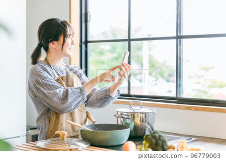 亞洲家庭主婦在廚房用智能手機看太陽能電費 96779003