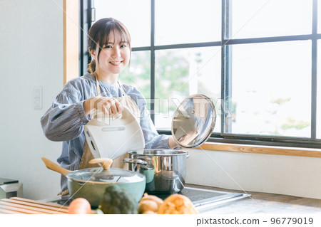 圍裙的亞裔婦女在廚房的電水壺裡放熱水 96779019