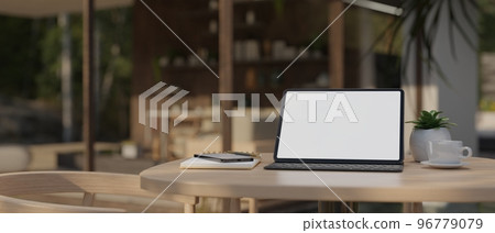 Portable tablet with wireless keyboard on wood table over blurred of beautiful coffee shop 96779079