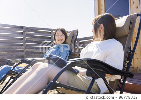 Sauna girls taking an open air bath in front of an outdoor sauna 96779312