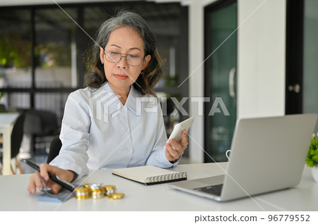 Professional Asian senior female accountant managing budget, using calculator Professional Asian senior female accountant managing budget, using calculator 96779552