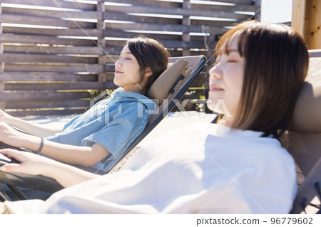 Two sauna girls taking an open air bath in front of an outdoor sauna Two sauna girls taking an open air bath in front of an outdoor sauna 96779602