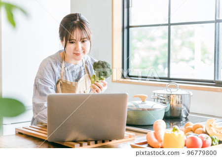 Asian woman searching for recipes and nutrients using laptop for cooking in home kitchen 96779800