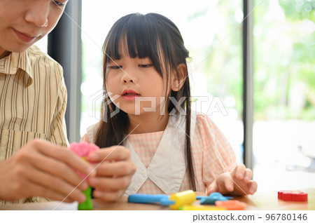 Cute Asian girl playing colorful clay, moulding play dough with her dad at home living room. Cute Asian girl playing colorful clay, moulding play dough with her dad at home living room. 96780146