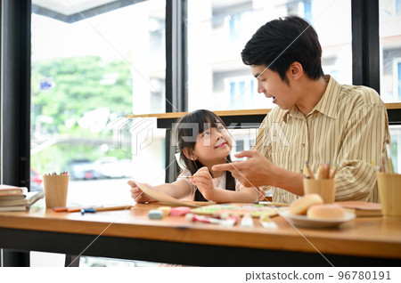 Smiling Asian male art teacher is teaching and having fun conversation with his young girl student Smiling Asian male art teacher is teaching and having fun conversation with his young girl student 96780191
