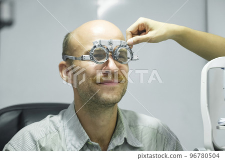 Man examining eyesight in optical clinic. Man examining eyesight in optical clinic. 96780504