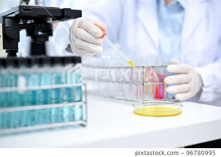 A professional chemist or scientist adjust liquid chemical samples in Petri dish. cropped image 96780995