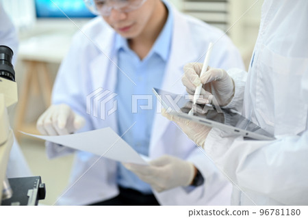 A female scientist working in the lab, recording the experiment results on the tablet 96781180
