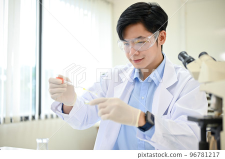 Smart Asian male scientist concentrating adjusts a virus sample in a Petri dish in his lab. Smart Asian male scientist concentrating adjusts a virus sample in a Petri dish in his lab. 96781217
