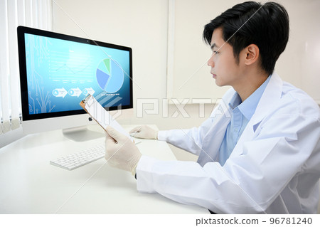 Handsome and smart Asian male doctor in white gown working at his office desk. Handsome and smart Asian male doctor in white gown working at his office desk. 96781240