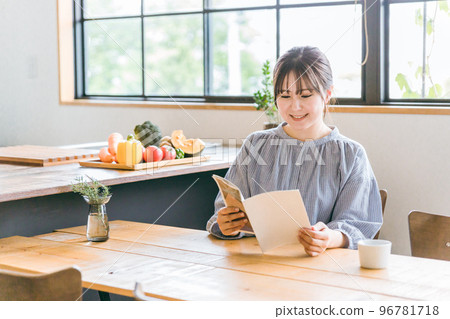 Asian woman drinking coffee while reading magazines and free papers at a cafe Asian woman drinking coffee while reading magazines and free papers at a cafe 96781718