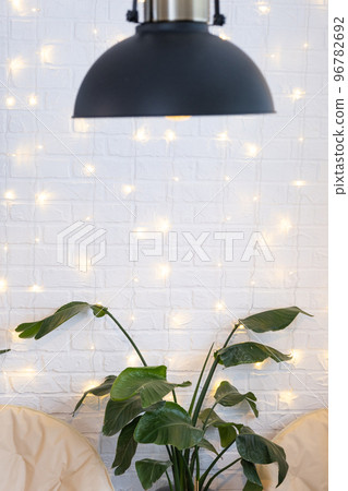 Christmas interior of a loft-style house with a black decorated retro lampshade and indoor plants of Strelitzia nicolai. New Year, comfort at home Christmas interior of a loft-style house with a black decorated retro lampshade and indoor plants of Strelitzia nicolai. New Year, comfort at home 96782692