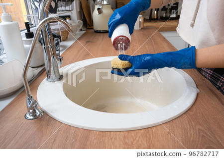 Cleaning sink in kitchen, Hand in gloves and sponge, detergent, dry powder. cozy interior of the home, restoring order, cleanliness, disinfection 96782717