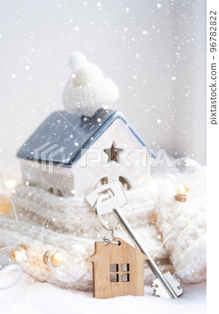 Key to the house with a keychain on a cozy home with a Christmas decor. A gift for New Year, Christmas. Building, design, project, moving to new house, mortgage, rent and purchase real estate Key to the house with a keychain on a cozy home with a Christmas decor. A gift for New Year, Christmas. Building, design, project, moving to new house, mortgage, rent and purchase real estate 96782822