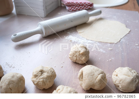 Hands knead thick dough, roll out with a rolling pin on the kitchen table, decorated with festive decorations for Christmas and New year. Baking at home, aroma and comfort. 96782865