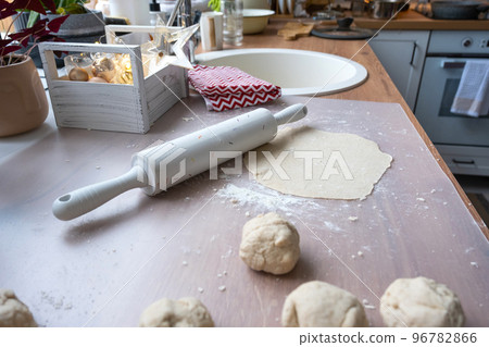 Hands knead thick dough, roll out with a rolling pin on the kitchen table, decorated with festive decorations for Christmas and New year. Baking at home, aroma and comfort. Hands knead thick dough, roll out with a rolling pin on the kitchen table, decorated with festive decorations for Christmas and New year. Baking at home, aroma and comfort. 96782866