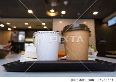 Fast food on a tray in a restaurant. French fries, a glass with a milkshake, coffee 96782873
