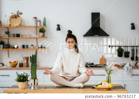 Young woman in lotus position sitting on the table Young woman in lotus position sitting on the table 96783217