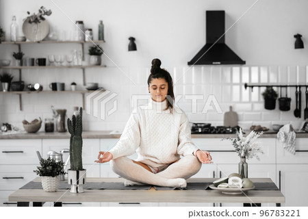 Young woman in lotus position sitting on the table 96783221