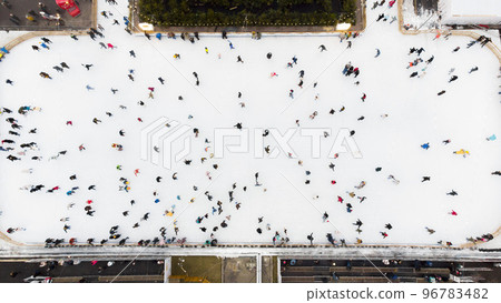 Top view of people skating on large open air ice rink on winter day. Aerial Drone View Flight Over crowd of people who skate on ice at rink. Winter sport activities. Skating background. City Ice Rink. 96783482