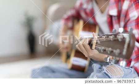 Close up fingers playing guitar strings, Strum to make a sound, Acoustic guitar, Catching guitar chords to create music, Music therapy and meditation practice with playing the guitar. 96783971