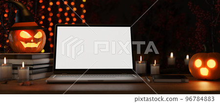 Modern dark working space with halloween decor, laptop mockup, candles, pumpkin lamps. Modern dark working space with halloween decor, laptop mockup, candles, pumpkin lamps. 96784883