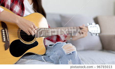 Close up fingers playing guitar strings, Strum to make a sound, Acoustic guitar, Catching guitar chords to create music, Music therapy and meditation practice with playing the guitar. 96785013