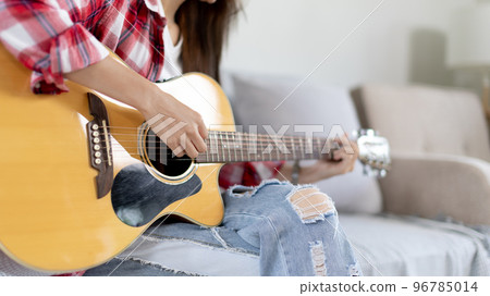 Close up fingers playing guitar strings, Strum to make a sound, Acoustic guitar, Catching guitar chords to create music, Music therapy and meditation practice with playing the guitar. 96785014