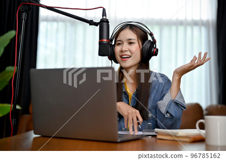 Happy Asian woman in headphones and professional microphone recording audio podcast 96785162