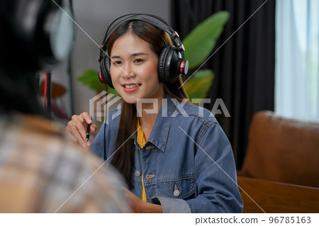 Confident Asian female radio host is recording her podcast and interviewing her guest Confident Asian female radio host is recording her podcast and interviewing her guest 96785163