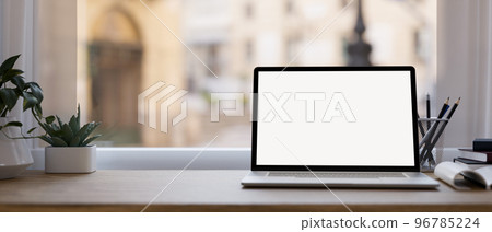 Modern office desk workspace with notebook laptop mockup and space on wood table over window Modern office desk workspace with notebook laptop mockup and space on wood table over window 96785224