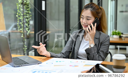 Attractive Asian businesswoman talking on the phone with her business supplier. Attractive Asian businesswoman talking on the phone with her business supplier. 96786292