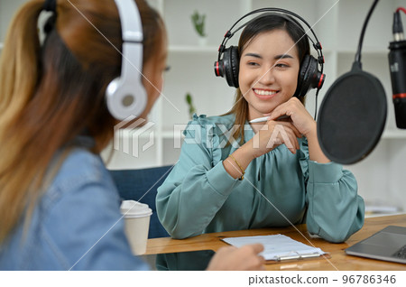 Professional Asian female podcaster enjoys interviewing her special guest in the studio. Professional Asian female podcaster enjoys interviewing her special guest in the studio. 96786346