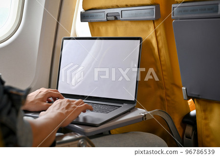 A male passenger in economy class using his portable laptop during the flight. close-up image 96786539