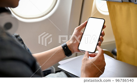 A male traveler passenger using his smartphone, holding a mobile phone white screen mockup. 96786540