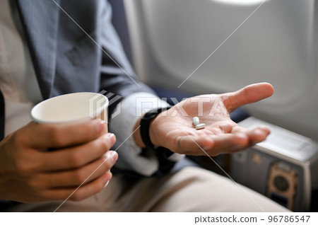 close-up, A male passenger holding a cup of water and an airsick motion sickness pills. 96786547