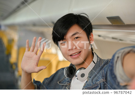 Handsome young Asian male travel blogger filming his travel vlog during the flight Handsome young Asian male travel blogger filming his travel vlog during the flight 96787042